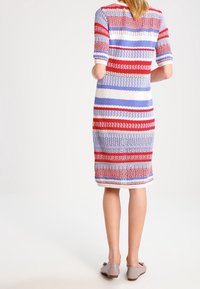 Kudotettu mekko lyhyillä hihoilla, jossa on vaakasuorat raidat punaisessa, valkoisessa ja sinisessä. Muotoileva siluetti ja polvipituinen malli.