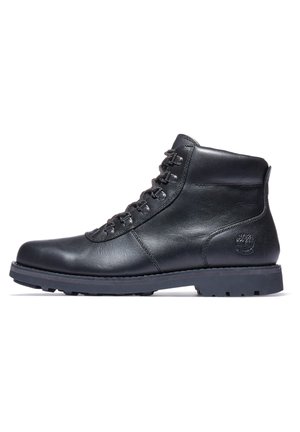 Czarny skórzany botek za kostkę z wyściełanym kołnierzem, metalowymi przelotkami, z przodu sznurowany, z wytrzymałą podeszwą i wytłoczonym logo Timberland po stronie pięty.