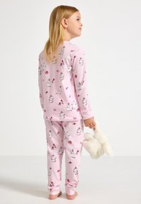 Różowy zestaw piżamowy z długimi rękawami i spodniami, ozdobiony wzorem z kreskówkowymi zwierzętami, sercami i prezentami. Miękka tkanina, luźny krój.