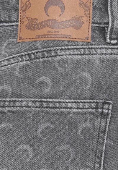 Pantaloni in denim grigio con tasca decorata da un sottile motivo a mezzaluna e etichetta in pelle marrone del brand Marine Serre cucita sopra.