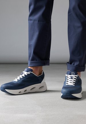 Baskets de sport bleues en mesh et matériaux synthétiques, avec des lacets blancs et une semelle gris clair avec des accentuations découpées.