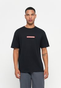 Black cotton t-shirt with short sleeves and a round neckline. Features a red rectangular logo reading "QUIKSILVER" on the chest.