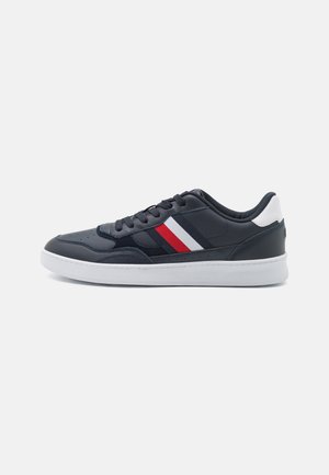 Sneaker di pelle blu navy con suola bianca, presenta strisce rosse e bianche ai lati, superficie testurizzata, punta tonda e design lacciato.