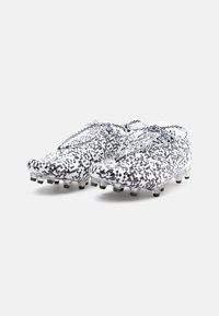 Scarpe da calcio con un design pixelato in bianco e nero, caratterizzate da un materiale sintetico leggero e da tacchetti chiari e modellati.