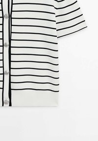 Cardigan blanc à manches courtes avec de fines rayures horizontales noires et des boutons argentés le long de l'ouverture frontale.