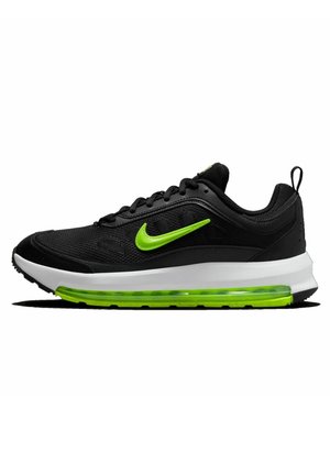 Zapatilla deportiva negra con parte superior de malla, swoosh verde de Nike, entresuela blanca acolchada y unidad de aire transparente verde en la suela.