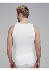 Vit bomullstopp med rundad halsringning, ärmlös design och figursydd passform. Tyget verkar slätt och är utan dekoration.