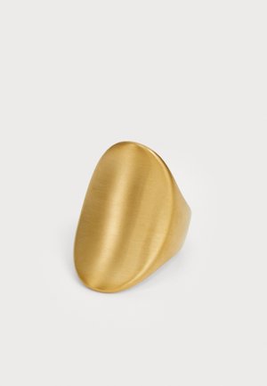 Bague en or mate et lisse avec une surface supérieure triangulaire arrondie et irrégulière, présentée sur un fond blanc uni.