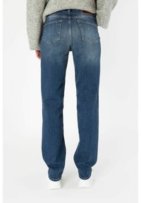 Modré džíny z denimu s rovným střihem, s dvěma zadními kapsami a jemným vyblednutím. Spárované s bílými teniskami a šedým svetrem.