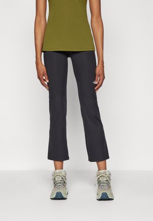 Un pantalon de sport gris foncé associé à un débardeur ajusté vert olive et des bottes de randonnée gris clair avec des accents violets et des semelles texturées.