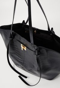 Borsa a spalla nera in ecopelle con stampa coccodrillo, dotata di due manici, accessori dorati e un interno aperto, caratterizzata da una texture liscia.