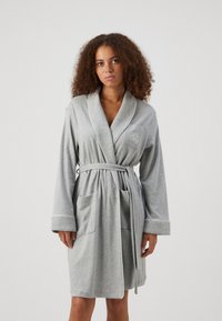 Roupa cinza com colarinho xale, design envolvente, dois bolsos frontais e um acabamento branco nas bordas. Feita de um tecido macio e texturizado.