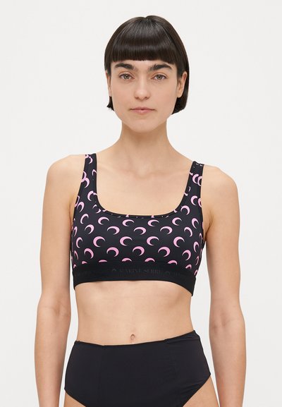 Brassière de sport noire avec motif de croissant de lune rose, encolure carrée, larges bretelles et bande noire unie avec le logo de la marque.