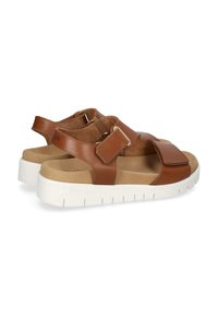 Brown leather sandals with adjustable straps, soft suede lining, and a white rubber sole featuring ridged texture and branding.