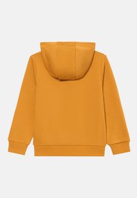 Sárga kapucnis pulóver puha textúrával, bordás mandzsettákkal és aljjal. Elöl zsebes, hátul pedig szépen varrott kapucnival rendelkezik.