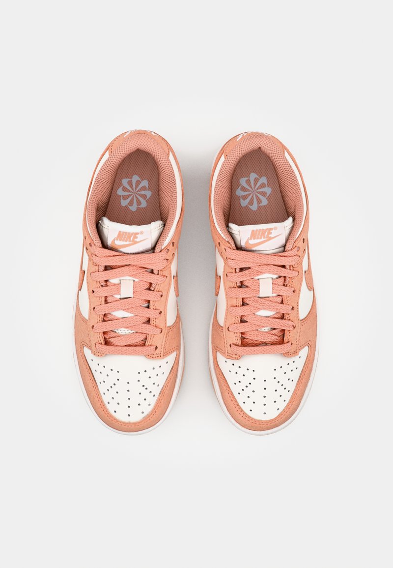 Baskets Nike avec un dessus en daim pêche doux, des accents en cuir blanc, une boîte à orteils perforée, des lacets plats et une semelle intérieure à motifs.