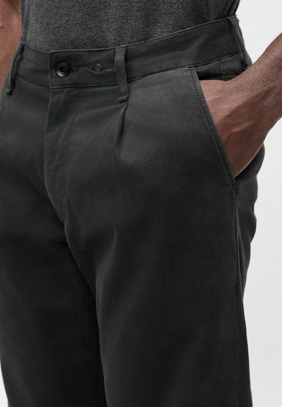 Črne hlače iz bombažnega mešanega materiala z gladko teksturo in ravnim krojem hlačnic. Imajo dva prednja žepa in gumbno zapiranje v pasu.