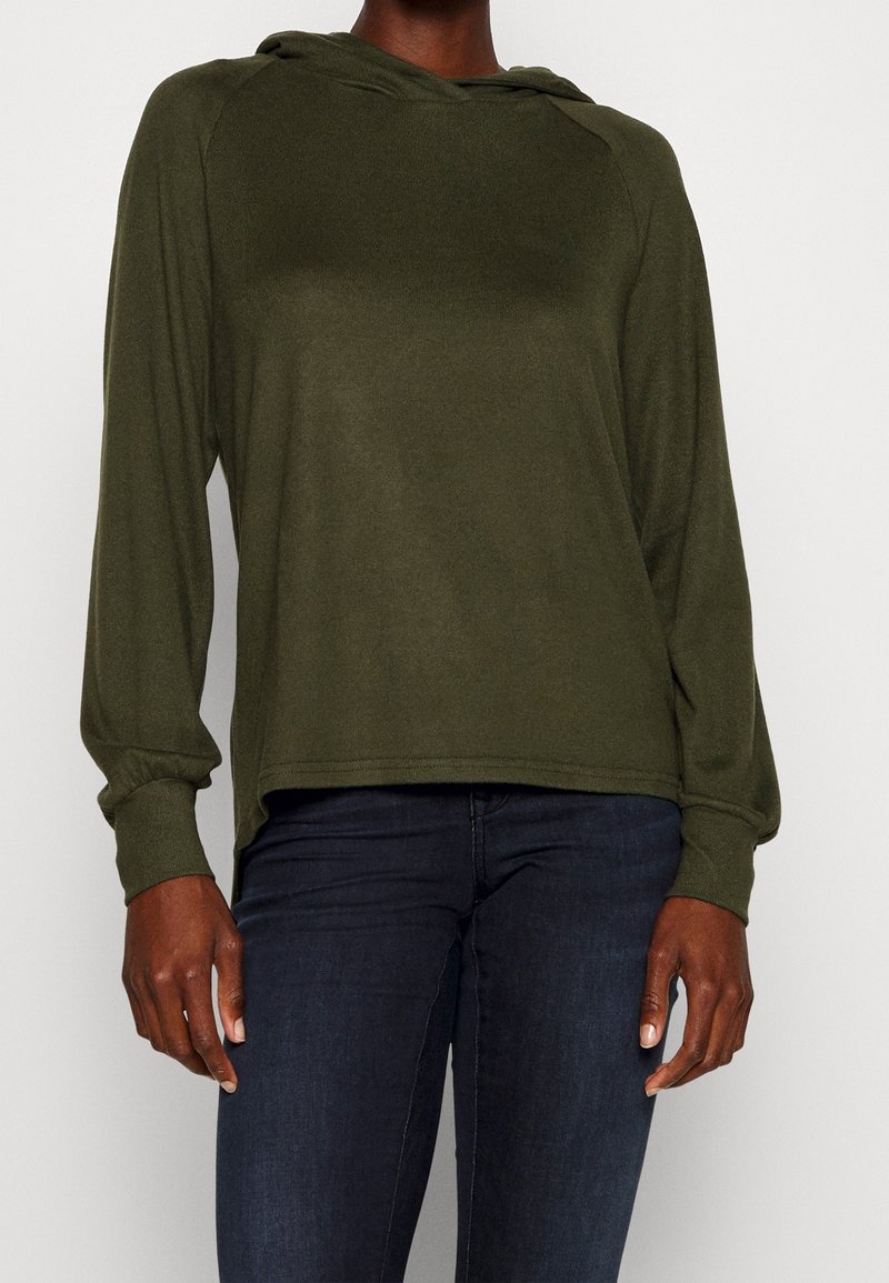 Olivgrön långärmad hoodie med en avslappnad passform. Har en justerbar huva och ribbade ärmslut, tillverkad av mjukt, lätt material.