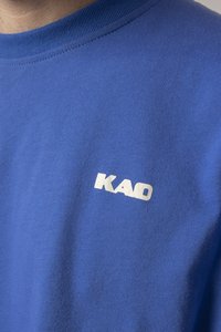 Blue cotton t-shirt featuring a ribbed neckline and a white "KAO" logo on the chest. Soft texture with a smooth finish.