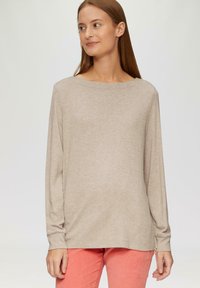 Beige langemouwen shirt met een brede halslijn, zachte textuur en relaxte pasvorm, gecombineerd met fel koraalkleurige broek.