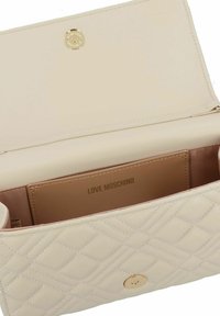 Borsa a tracolla beige trapuntata composta da pelle liscia. Presenta accessori in oro e uno scomparto interno per schede con la scritta "LOVE MOSCHINO" in rilievo.