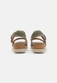 Grønne semskede sandaler med åpen bak, justerbare stropper og en chunky beige platåsåle med tre-lignende detaljer.