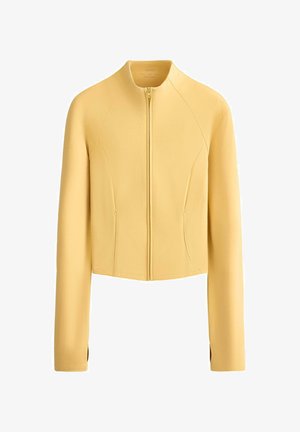 Világos sárga, rövidített kabát hosszú ujjakkal, elülső cipzárral és karcsúsított szabással.