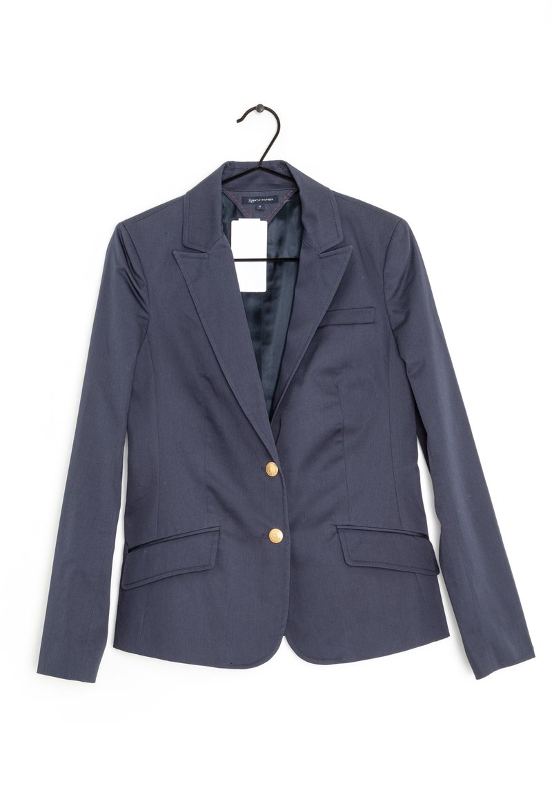 Námořnický blejzr s jednoduchým zapínáním na jeden řad, zlaté knoflíky, dvě přední kapsy a saténová podšívka viditelná v oblasti límce.