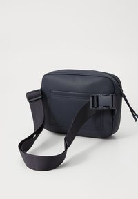 Geantă rectangulară de culoare bleumarin, confecționată din material texturat, având o curea detașabilă și un compartiment frontal cu închidere prin cataramă tip snap.