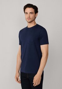 Camiseta de algodón de manga corta color azul marino con escote redondo y bolsillo que presenta un sutil detalle de logo bordado.