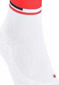 Calzino bianco alla caviglia con strisce rosse, bianche e nere vicino al bordo e un piccolo logo rosso nella zona delle dita.