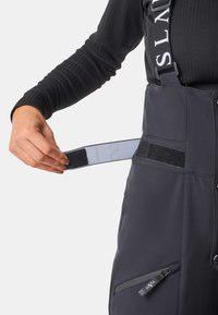 Zwarte geïsoleerde sneeuwbroek met verstelbare banden, een gestructureerde afwerking, zijzakken met rits en klittenbandaccenten voor een veilige pasvorm.