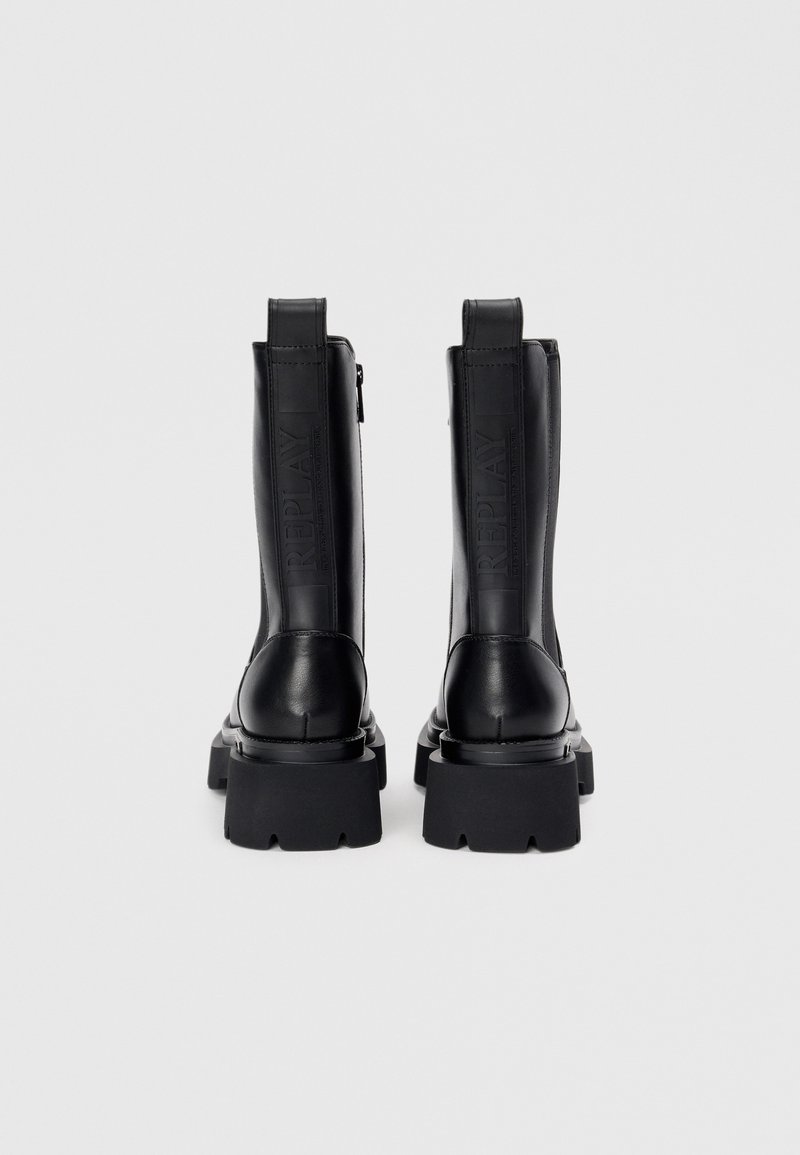 Stivali alla caviglia in pelle nera con suola spessa, cerniere laterali e marchio impresso sul lato, dotati di caratteristiche tiranti distintivi per facilitare la calzata.