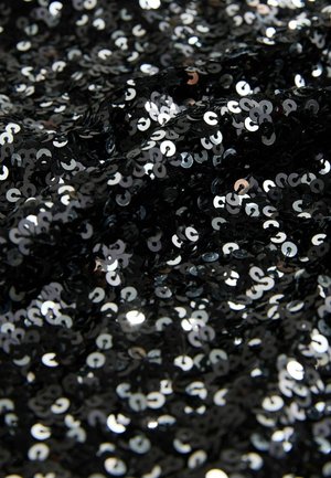Schwarzer Stoff, der mit glänzenden, reflektierenden, runden Pailletten bedeckt ist. Die Textur wirkt glatt, mit unterschiedlichen Lichtreflexionen auf der Fläche.