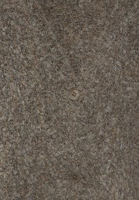 Brun texturerad kofta med en fluffig yta, med V-halsdesign och en knappstängning i ljusbrun plast.