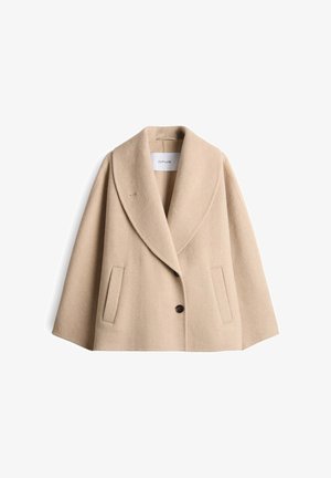 Beige wollen korte jas met een brede sjawl-kraag, twee zijzakken en twee donkere knopen, gelabeld "OPUS" aan de binnenkant van de kraag.
