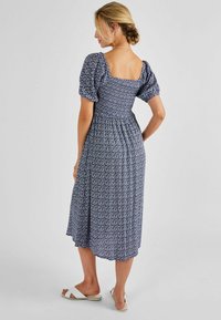 Rochie midi cu model floral, de culoare albastră închisă, cu mâneci bufante și decolteu pătrat. Dispune de un corset elastic și o fustă fluidă.