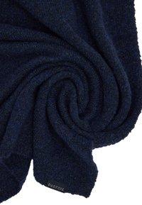 Granatowy dziany szalik o miękkiej fakturze, zwiniętym wzorze oraz małej metce z nazwą marki "PARFOIS" widoczną na nim.