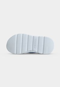 Λευκή σόλα παπουτσιού Skechers, ορατή από κάτω, με βαθιές οριζόντιες αυλακώσεις και αποτύπωμα λογότυπου στο κέντρο.