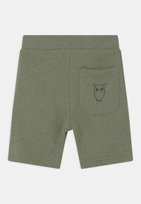 Olivgrüne Shorts mit elastischem Bund und einer Gesäßtasche, die ein kleines schwarzes Eulen-Graphic zeigt.