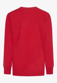 Camisa roja de manga larga con cuello redondo, que presenta una textura suave y puños ajustados. No hay patrones ni adornos visibles.