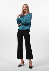 Teal satengbluse med knappestolpe, ballongsleeves; kombinert med svarte flagrende bukser og svarte spisse hæler.
