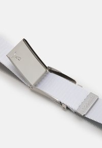 Hvit vevd belte med sølvfarget metallspenne. Spennen har inngravert logo og teksturert grep. Justerbar lengde med slank, minimalistisk design.
