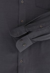 Dunkelgraues, strukturiertes Hemd mit Button-Down-Kragen, vier Knöpfen und geknöpften Manschettendetails. Taschen auf der rechten Seite.