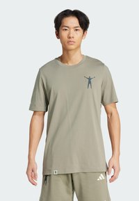 Short-sleeve, olive green cotton t-shirt with a printed figure design on the chest and a logo tag at the hem. Smooth texture.