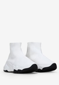 Zapatillas blancas de estilo calcetín con un upper acanalado, suela con amortiguación y suela exterior de goma negra. Ligeras, de textura suave y con un diseño elegante.