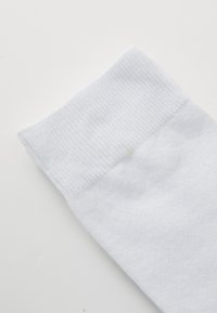 Weißer Baumwollsocken mit einem gerippten Bündchen, glatter Textur, leicht schräg an der Oberkante und minimal sichtbaren Nähten.