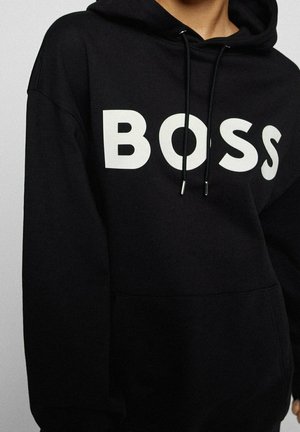 Felpa nera realizzata in materiale morbido con un grande logo bianco "BOSS" sul davanti, cappuccio con cordino e tasca a marsupio frontale.