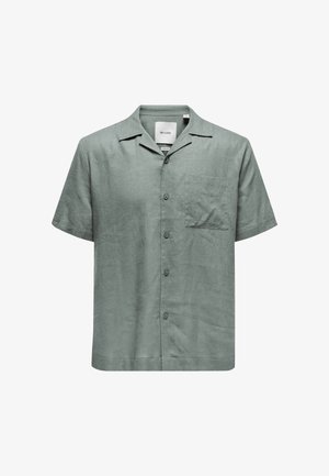 Koszulka z krótkim rękawem, zielona, wykonana z lnu, z zapięciem na guziki, kołnierzykiem typu spread, pojedynczą kieszonką na piersi i luźnym krojem. Widoczny szczegół teksturowanego materiału.