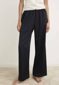 Pantalones de satén negros de pierna ancha con cinturilla elástica y cordón de ajuste. Textura suave y diseño fluido adecuados para el uso diario.